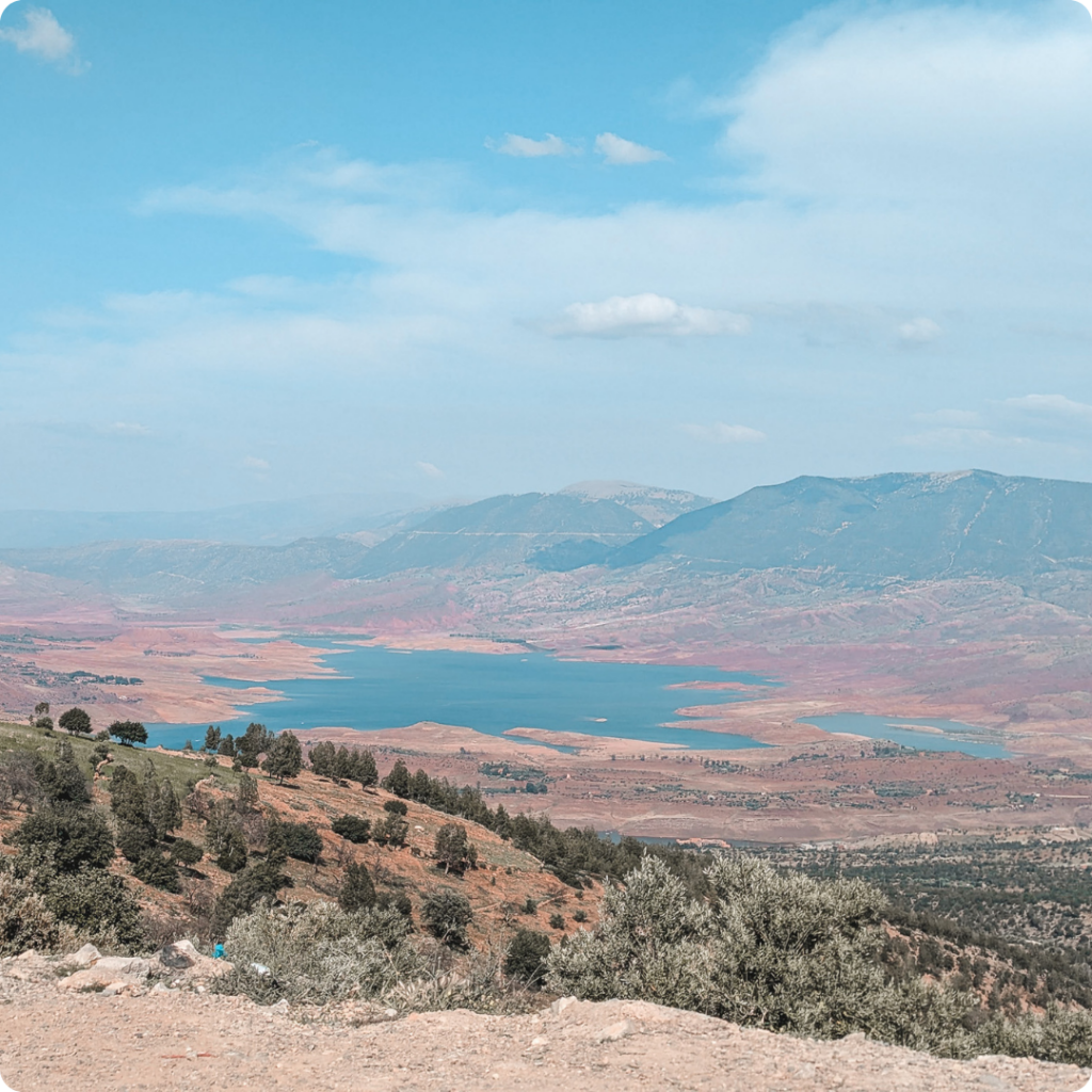 Stunning panoramic view of Bin el Ouidane Lake in Morocco, framed by rolling hills and the Middle Atlas Mountains—ideal for travel advisors promoting tranquil, nature-filled retreats and scenic inland routes between Marrakech and Fes.